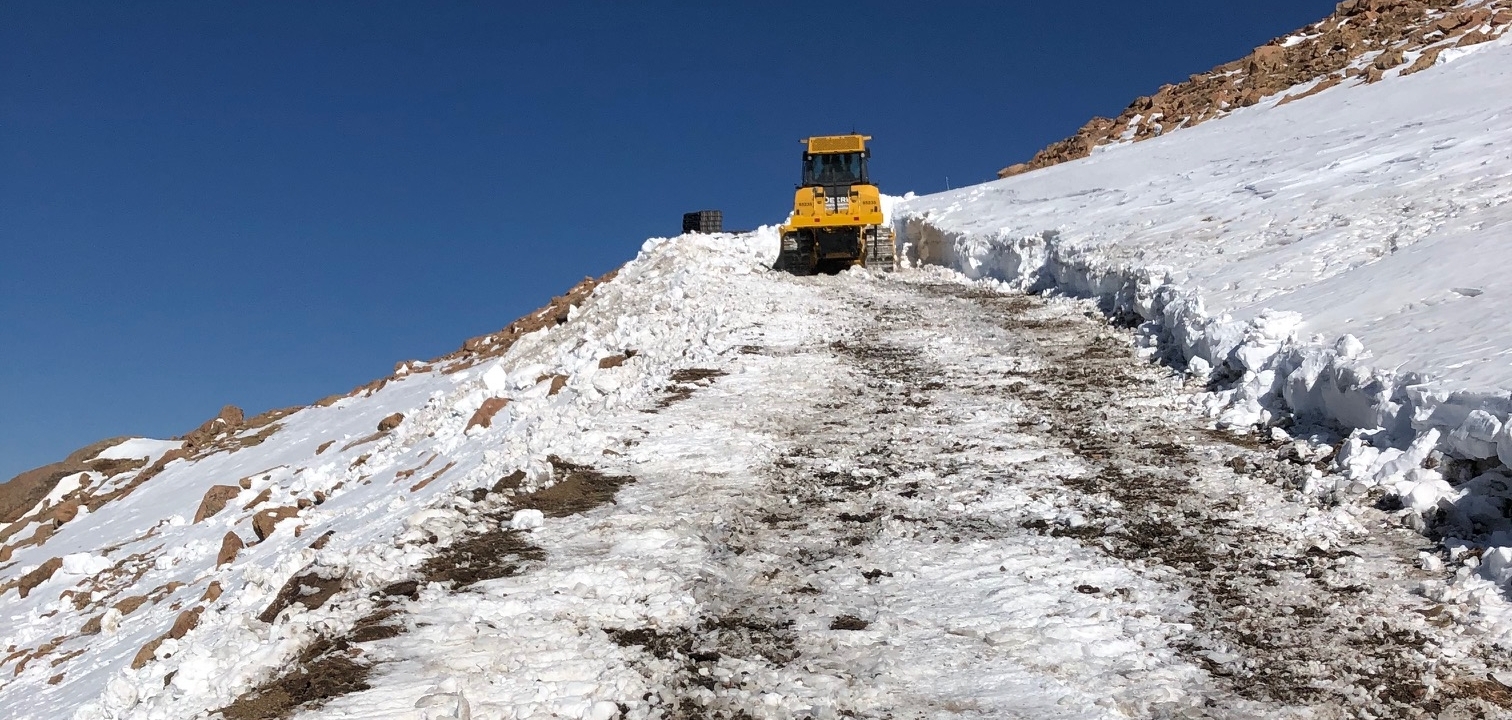 A truck driving over snow at the top of Pikes Peak Mountain