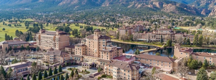 Aerial view of resort hotel on sunny morning with mountains and blue skies