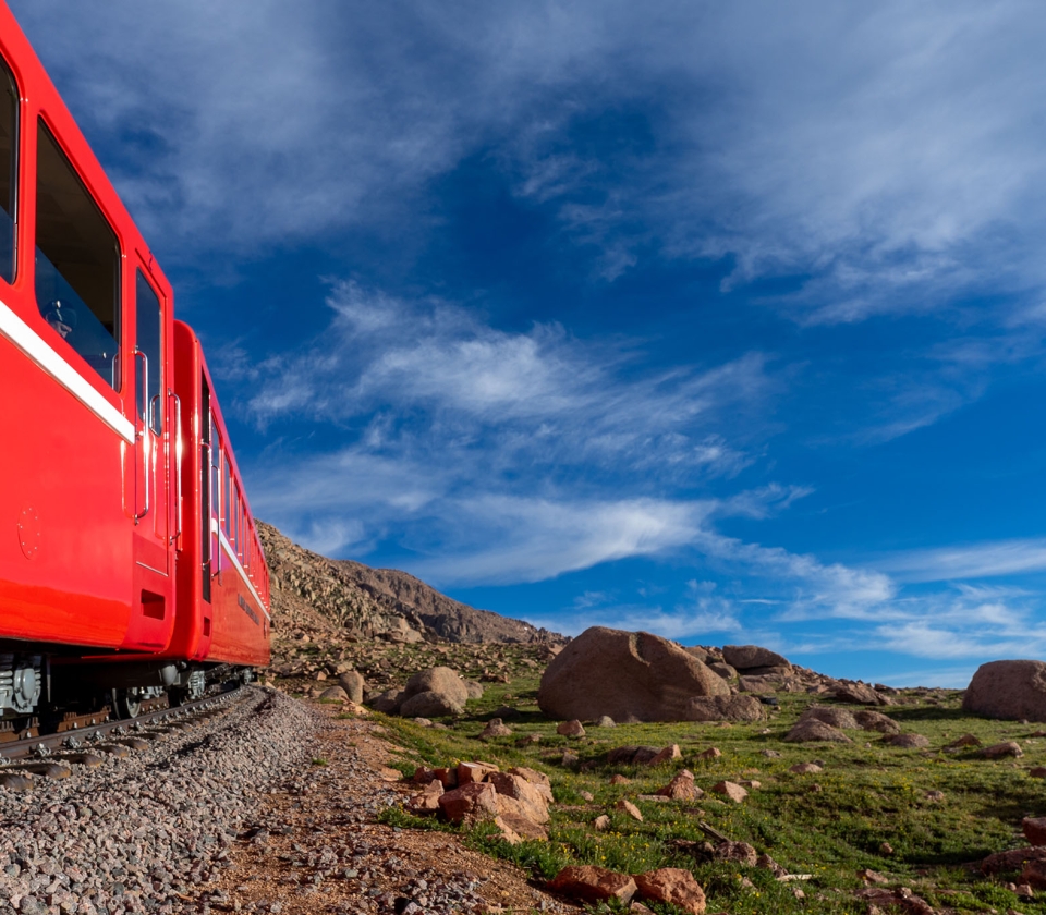 Red train on tracks during sunset