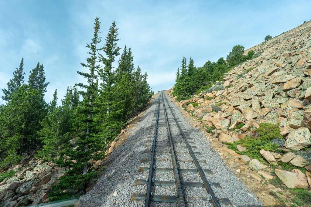  Empty train tracks and green trees on a mountain