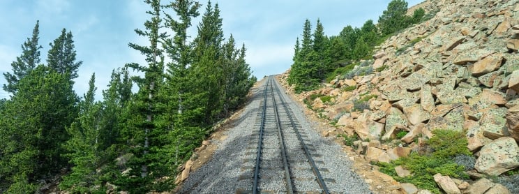 Empty train tracks and green trees on a mountain