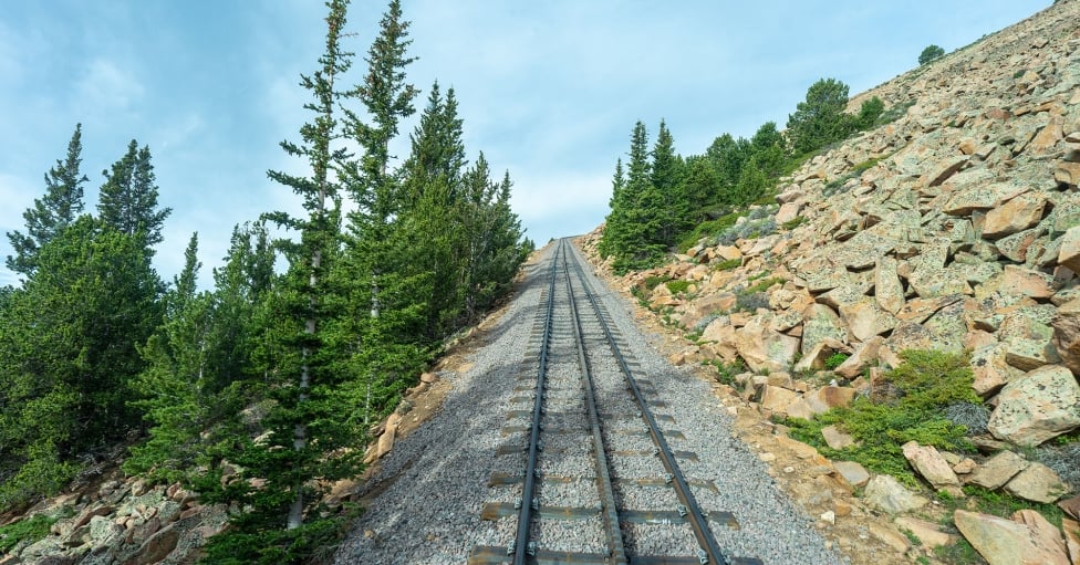 Empty train tracks and green trees on a mountain