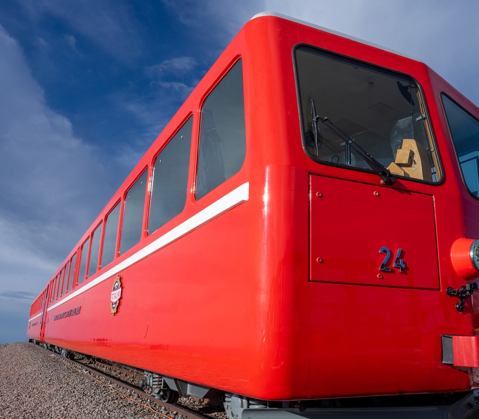 Red train on tracks with blue skies and clouds