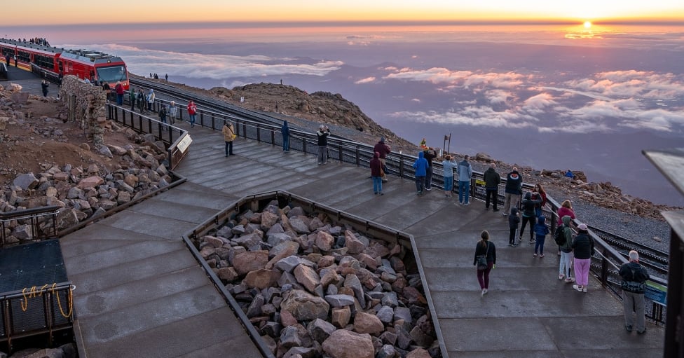 A Group Of People Walking On A Bridge Over A Body Of Water